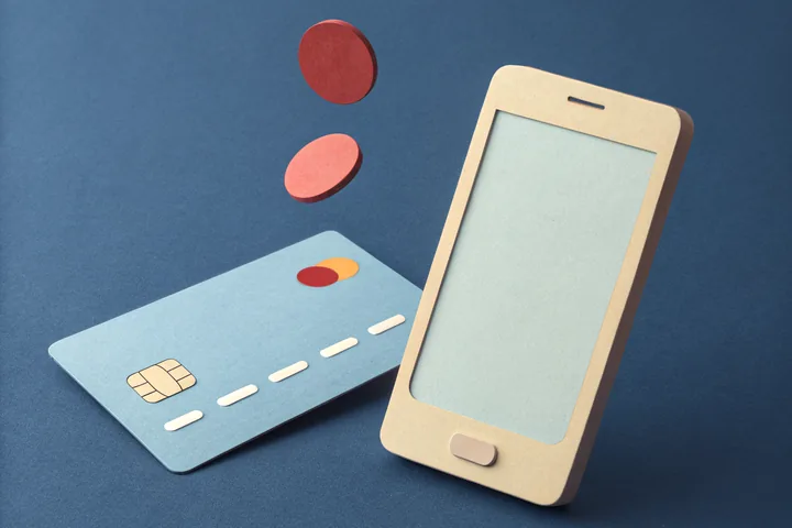 Paper cut illustration of a bank card and a phone with a coin passing between them, for the payment method guides